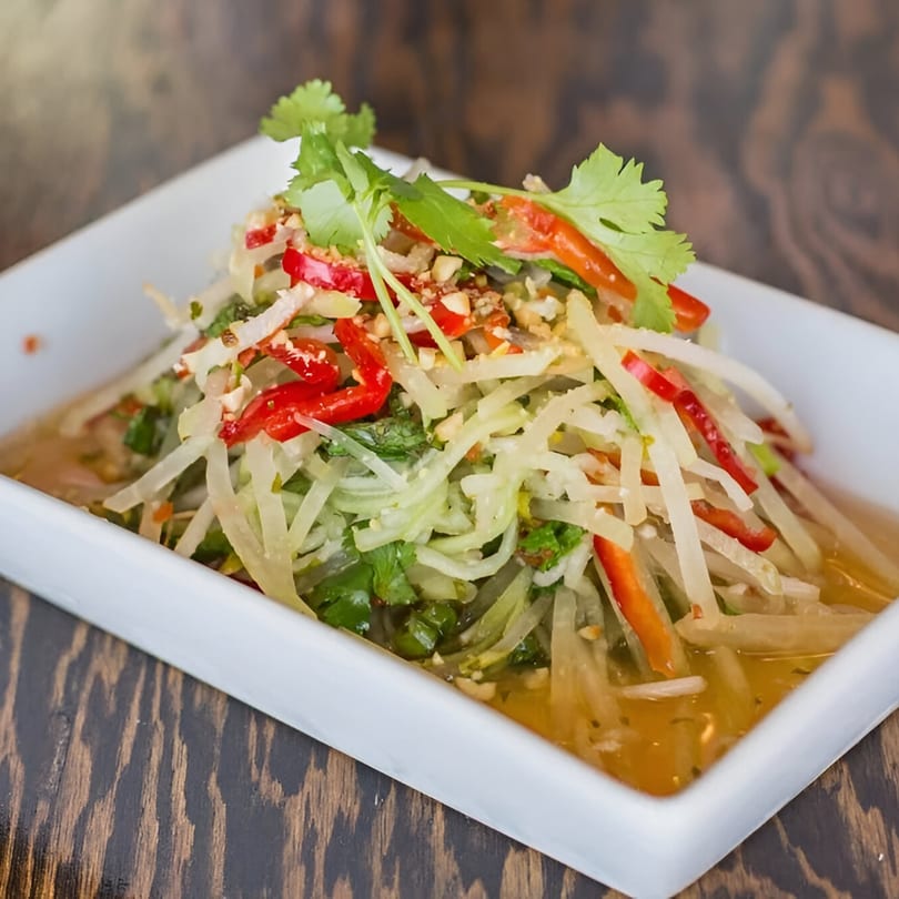 Feu Pho Kitchen's Vietnamese papaya salad with red peppers, peanuts, and cilantro in a white bowl.