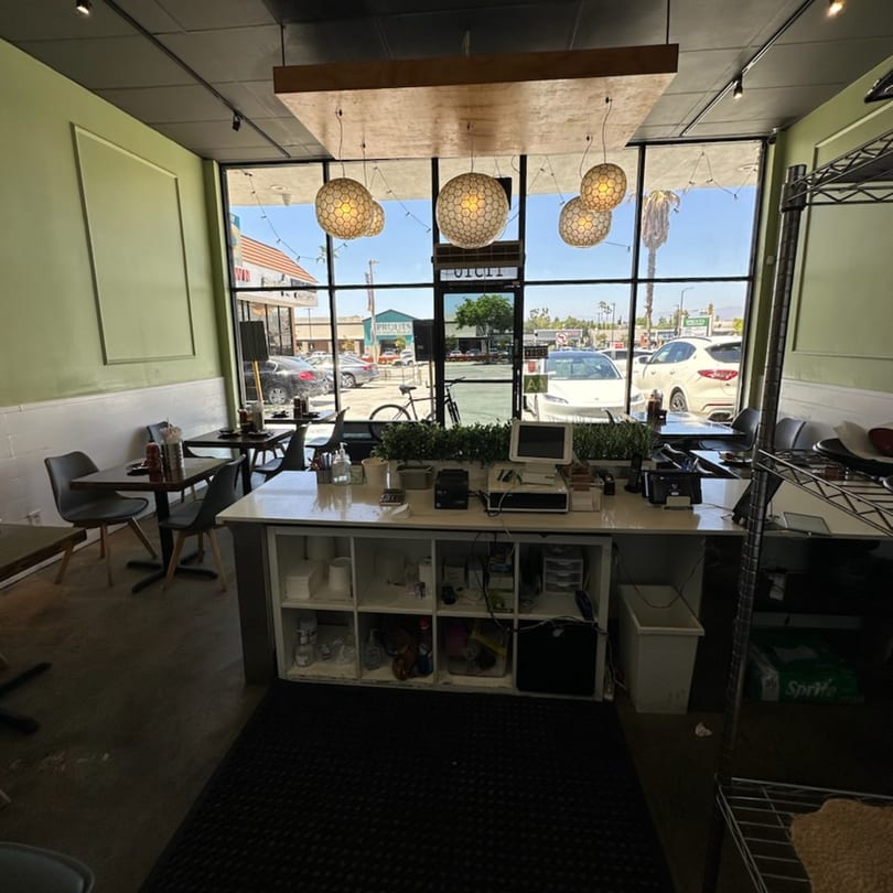 Interior of Feu Pho Kitchen, showing the front counter, dining tables, and large windows.