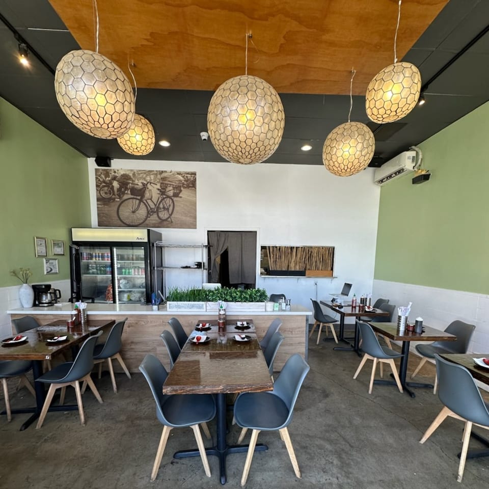 Feu Pho Kitchen's dining area with modern tables, chairs, and unique honeycomb-patterned pendant lights.