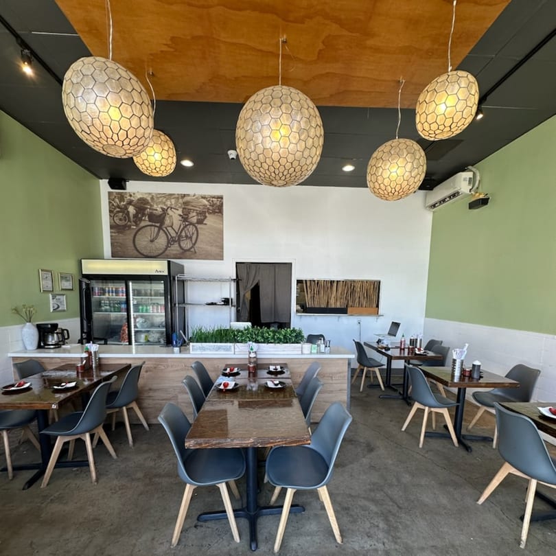 Feu Pho Kitchen's dining area with modern tables, chairs, and unique honeycomb-patterned pendant lights.